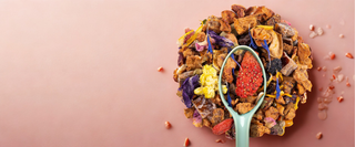 Mélange de thé en vrac avec fruits séchés, fleurs et baies sur fond rose